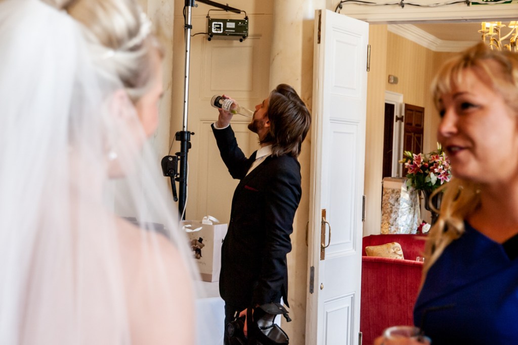 A guest take a swig of beer from a bottle at Shropshire wedding venue, Rowton Castle.