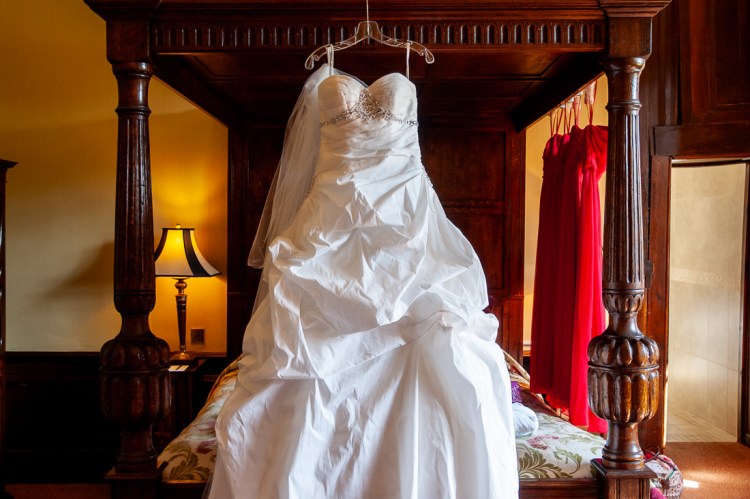 The bride's dress hangs from a four-poster bed, ahead of a wedding at Rowton Castle in Shropshire.