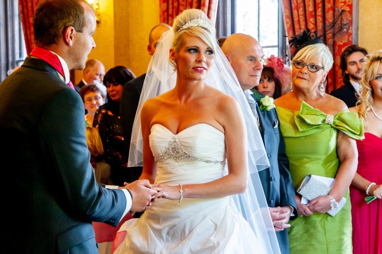 The bride and groom hold hands during the ceremony at a wedding at Rowton Castle in Shropshire.