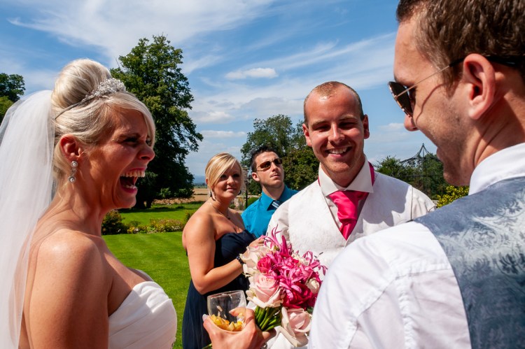 The bride and groom laugh with a guest during a wedding at Rowton Castle in Shropshire.