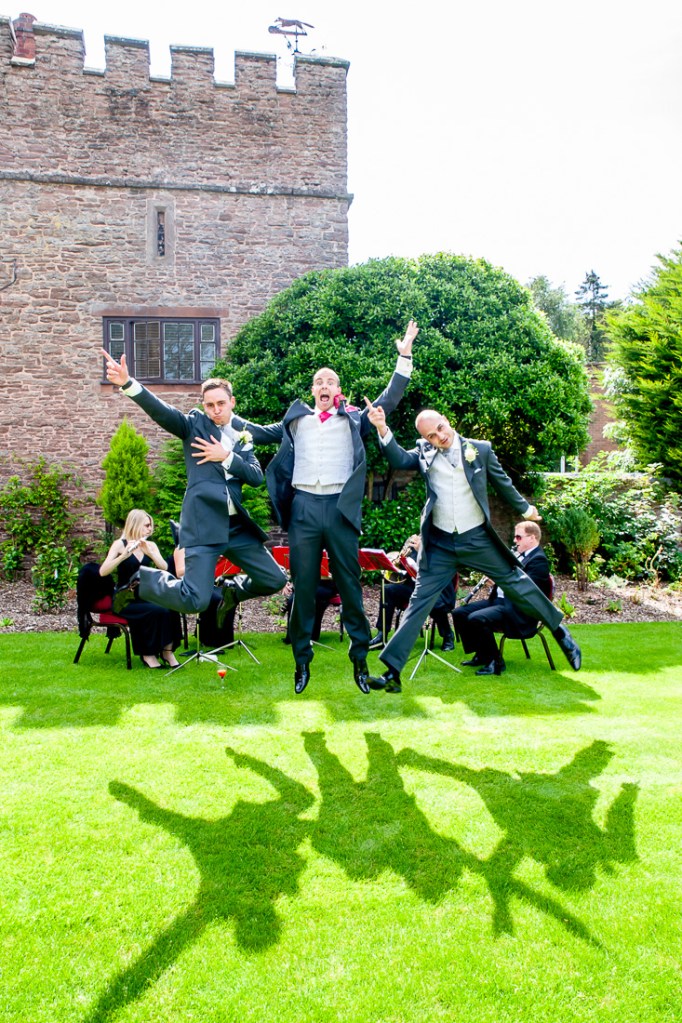 The groom and best man jumping in the air during a wedding at Rowton Castle in Shropshire.