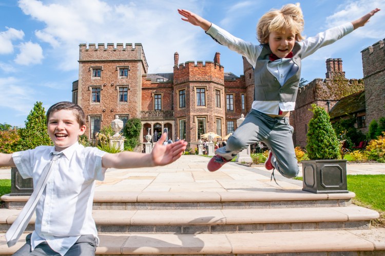 Two young guests leaping around in the grounds, during a wedding at Rowton Castle in Shropshire.