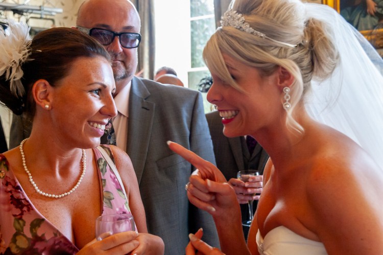 The bride amusingly points at a guest during a wedding at Rowton Castle in Shropshire.