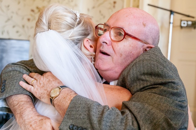 An elderly male guest hugs the bride during a wedding at Rowton Castle in Shropshire.