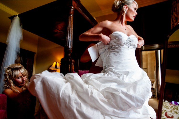The bride is helped into her dress, before a wedding at Rowton Castle in Shropshire.