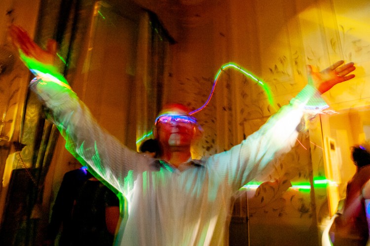 A guest in glasses and arms raised on the dancefloor, during a wedding at Rowton Castle in Shropshire.