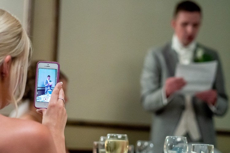 A guest films the groom during his speech, at a wedding at the Holiday Inn Seafront hotel in Brighton, East Sussex.