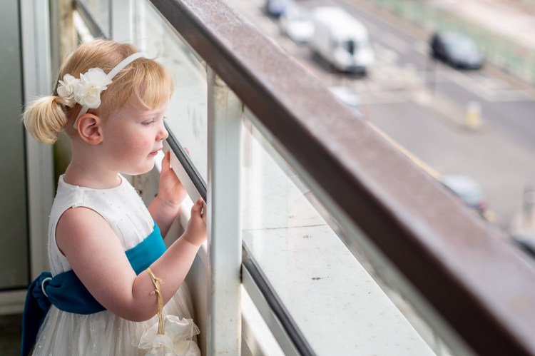 The flower girl looks down at traffic, ahead of a wedding at the Holiday Inn Seafront hotel in Brighton, East Sussex.