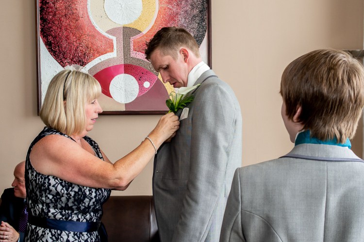 The groom gets help with his buttonhole flower, before a wedding at the Holiday Inn Seafront hotel in Brighton, East Sussex.