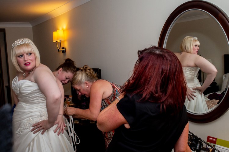 The bride is helped with her dress ahead of a wedding at the Meon Valley Hotel, near Southampton, in Hampshire.