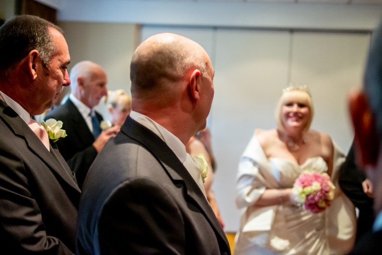THe groom looks on as the bride arrives for a wedding ceremony at the Meon Valley Hotel, near Southampton, in Hampshire.