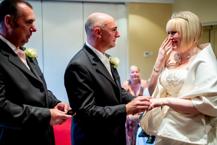 THe bride giggles during the grooms vows, at a wedding ceremony  at the Meon Valley Hotel, near Southampton, in Hampshire.