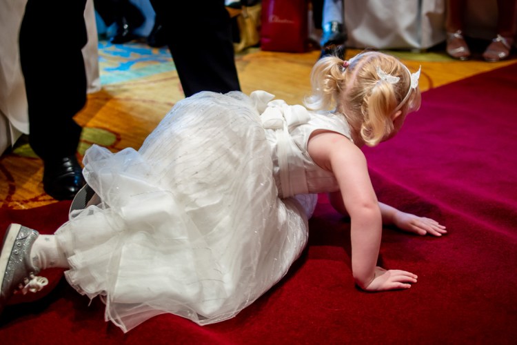 The flower girl crawls on a red carpert during a wedding ceremony at the Meon Valley Hotel, near Southampton, in Hampshire.