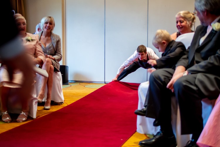A member of the staff sorts out the red carpet during a wedding ceremony at the Meon Valley Hotel, near Southampton, in Hampshire.