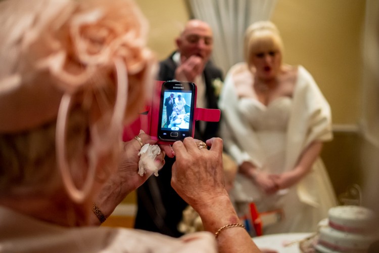 A guest takes a photo of the bride and groom, during a wedding ceremony at the Meon Valley Hotel, near Southampton, in Hampshire.