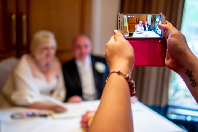 Another guest takes a photo of the bride and groom during a wedding at the Meon Valley Hotel, near Southampton, in Hampshire.