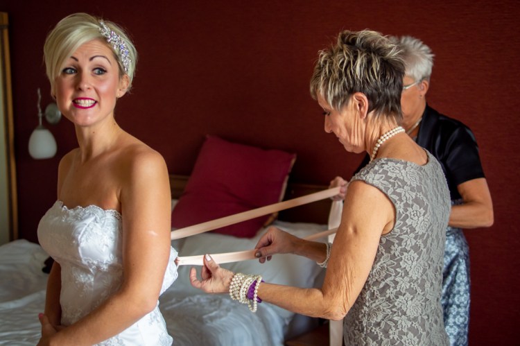 The bride is helped into her dress, ahead of a wedding at the Old Ship Hotel in Brighton, East Sussex.