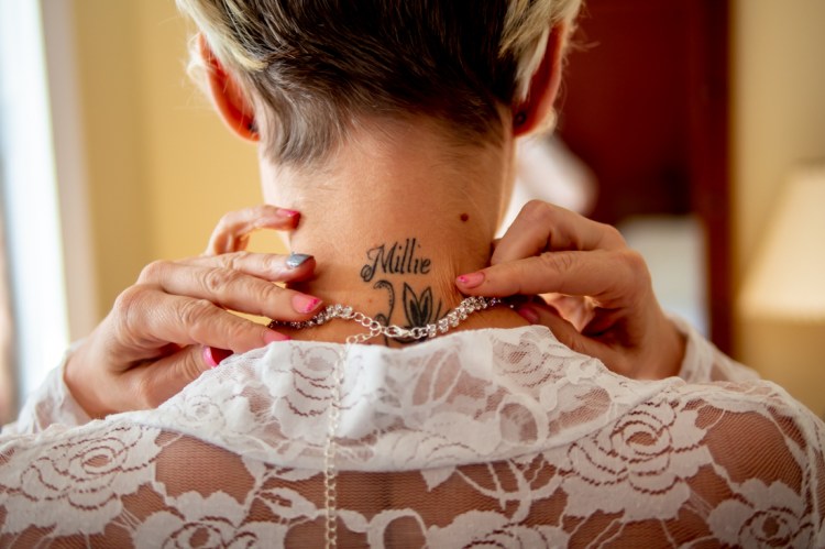 The bride puts on a necklaces, ahead of a wedding at the Old Ship Hotel in Brighton, East Sussex.
