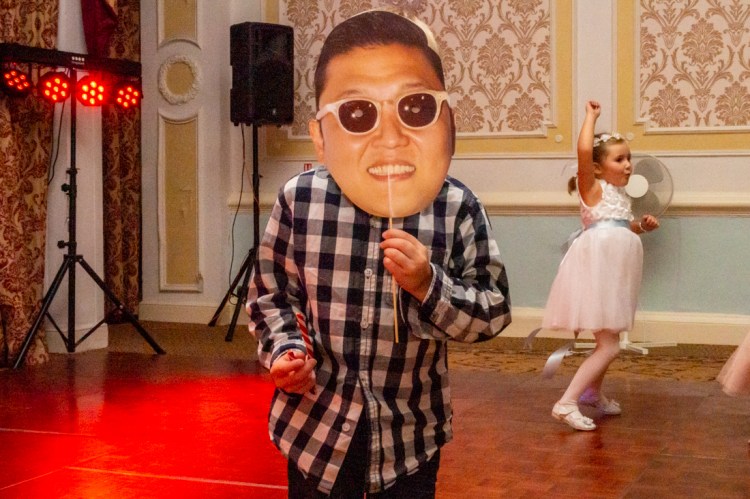 A young guest with a PSY mask, as another dances in the background, during a wedding at the Old Ship Hotel in Brighton, East Sussex.