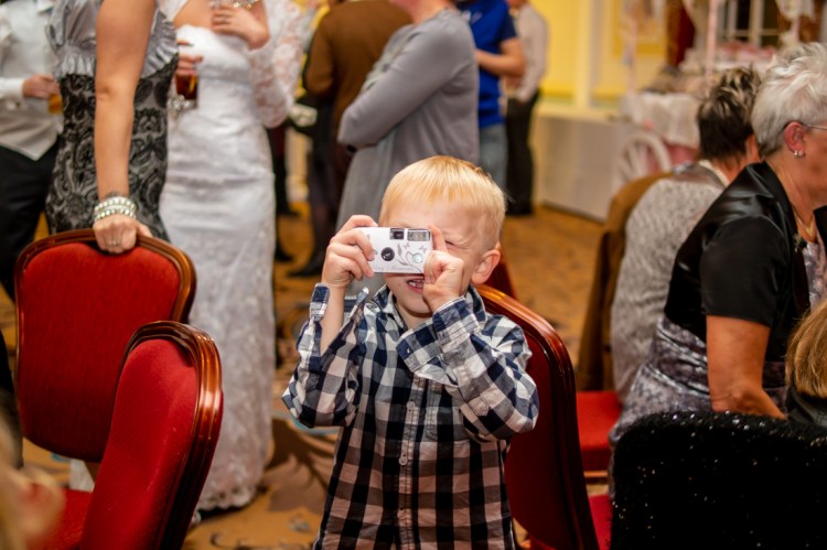 A young guest with a camera during the evening wedding reception at the Old Ship Hotel in Brighton, East Sussex.