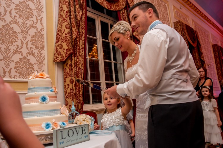 The bride, groom and their daughter cut the cake, during the evening wedding reception at the Old Ship Hotel in Brighton, East Sussex.