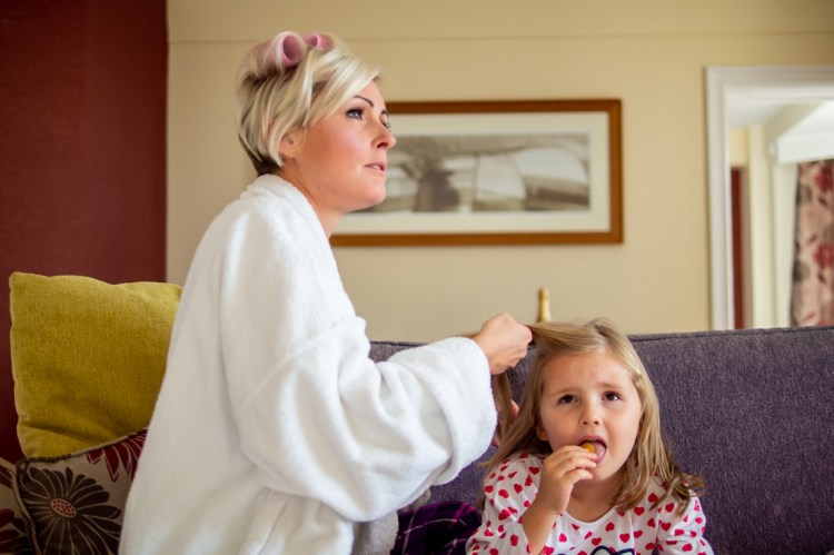 The bride does her daughters hair, before a wedding at the Old Ship Hotel in Brighton, East Sussex.