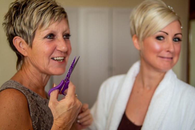 The bride pulls a funny expression as her mother holds up a pair of scissors, ahead of a wedding at the Old Ship Hotel in Brighton, East Sussex.