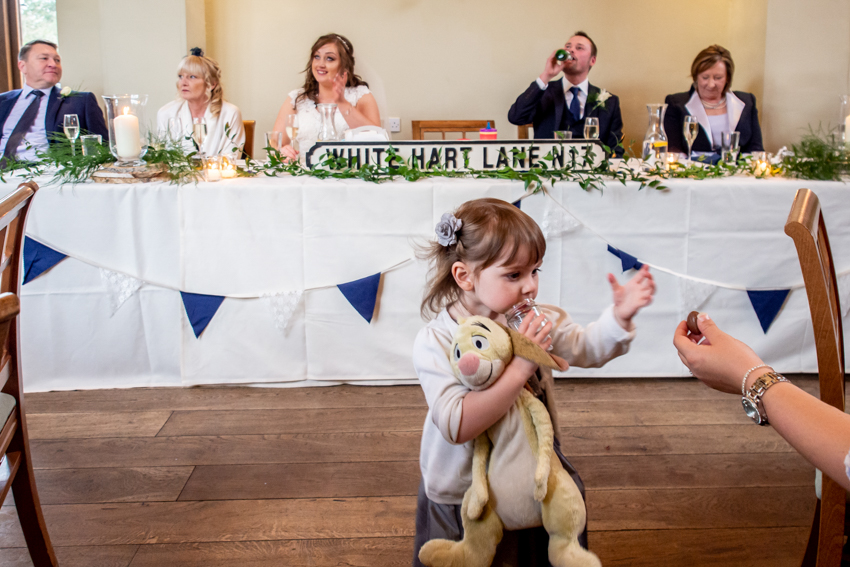 Documentary wedding photography of a young wedding guest with a cuddly toy, during the wedding speeches at Dodmoor House in Northamptonshire. Taken by Bristol wedding photographer, Darren Lehane.