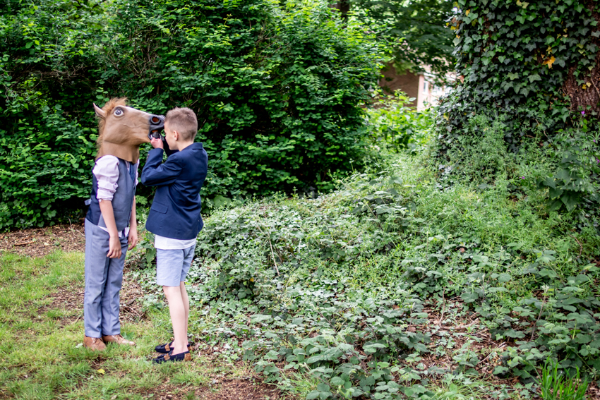 Candid wedding photography of a young guest wearing a horse mask, during a wedding at the Barns At Hunsbury Hill in Northampton. Taken by Bristol wedding photographer, Darren Lehane.