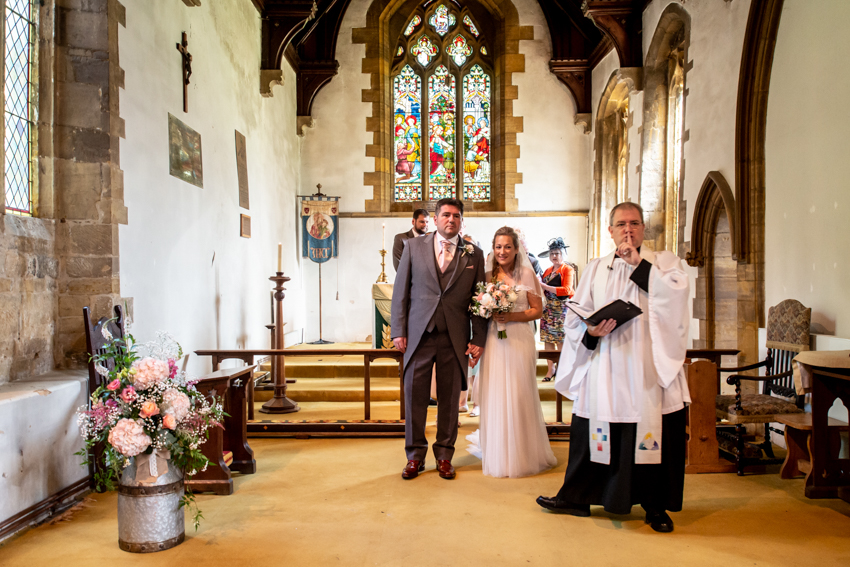Documentary wedding photography of the vicar hushing the congregation during a wedding in Nether Heyford, Northamptonshire. Taken by Bristol wedding photographer, Darren Lehane.