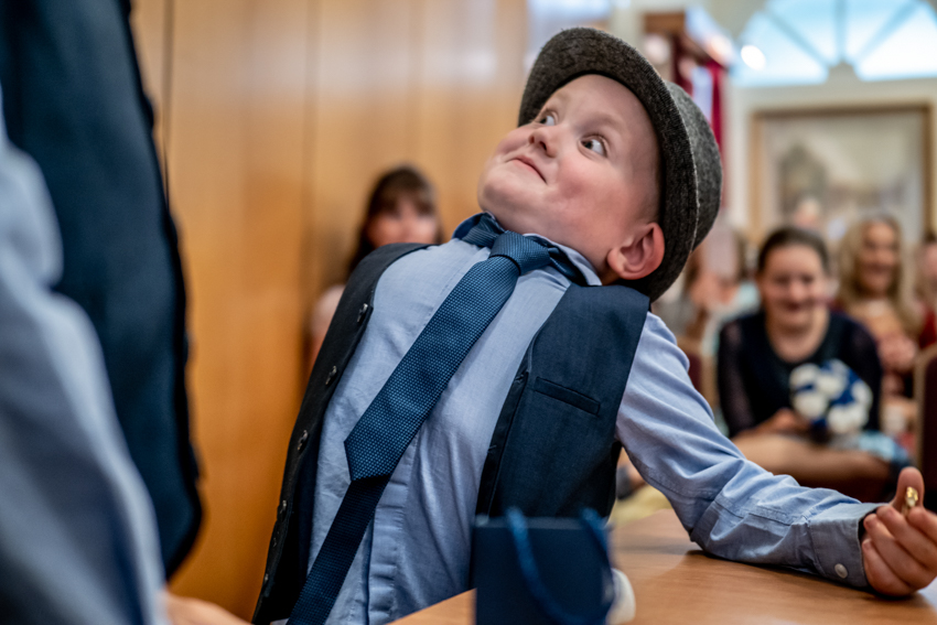Wedding photojournalism of a young ringbearer pulling a funny face during a wedding at Kettering Registry Office in Northants. Taken by Bristol wedding photographer, Darren Lehane.