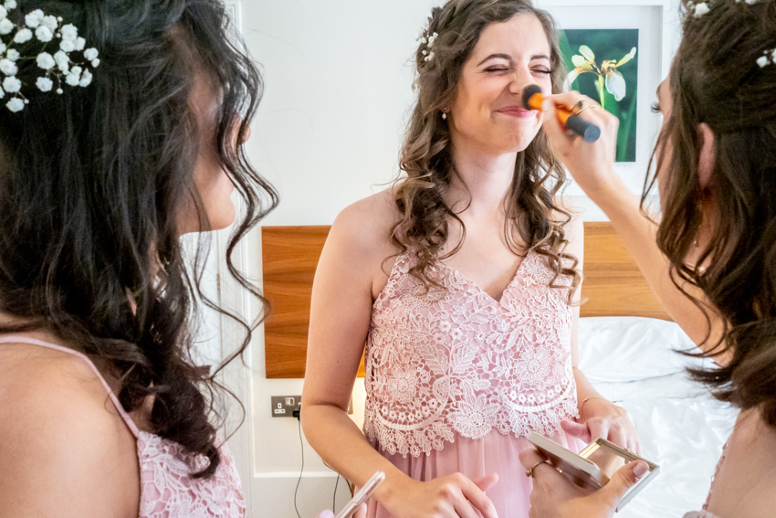 Candid wedding photography of a bridesmaid having her makeup applied before a wedding at Worcester College in Oxford. Taken by Bristol wedding photographer, Darren Lehane.