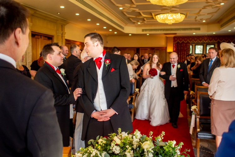 Wedding photojournalism of the groom being reassured as the bride comes down the aisle, at the South Lodge Hotel in Horsham, Sussex. Taken by Bristol wedding photographer, Darren Lehane.