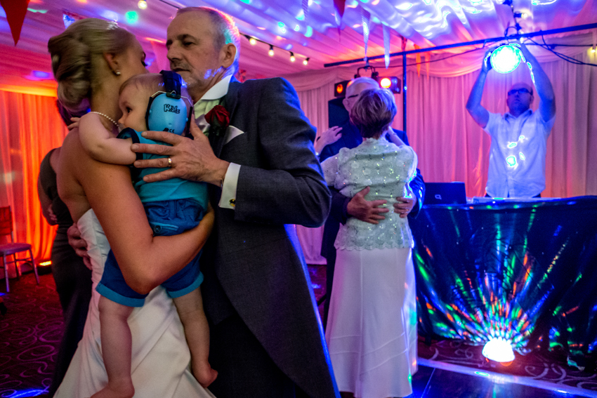 Natural wedding photography of a bride, son and her father on the wedding dancefloor at Sedgebrook Hall in Northamptonshire. Taken by Bristol wedding photographer, Darren Lehane.