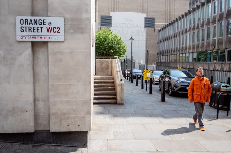 Candid street photography of a man wearing orange on Orange Street in central London.