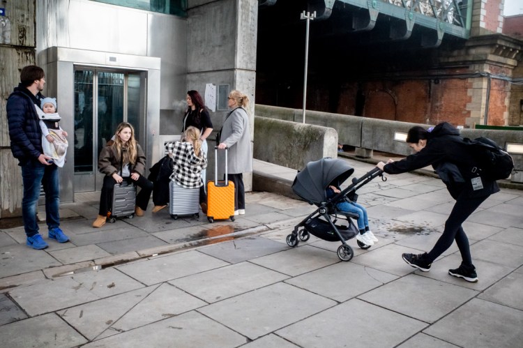 A family gather under the Golden Jubilee Bridge on the South bank in LOndon. Candid street photography by Darren Lehane