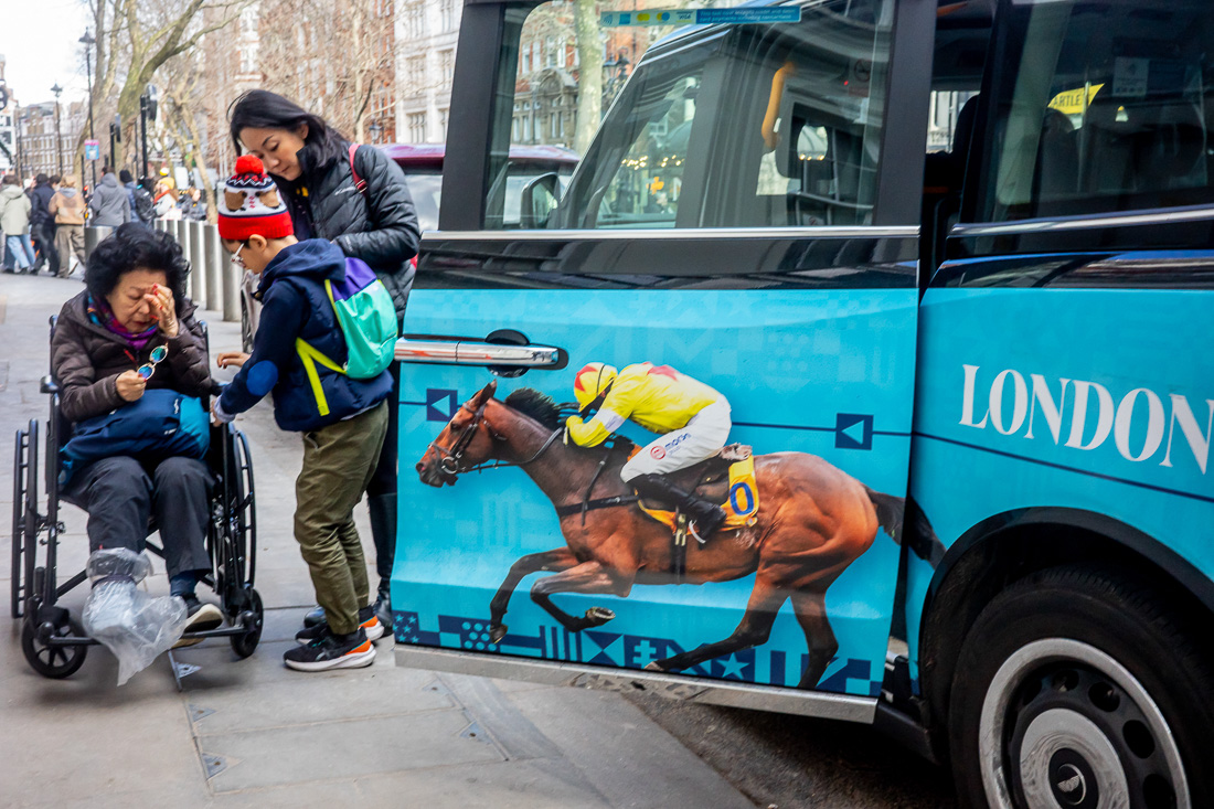 A woman in a wheelchair grimaces as a horse on some advertising races toward her.