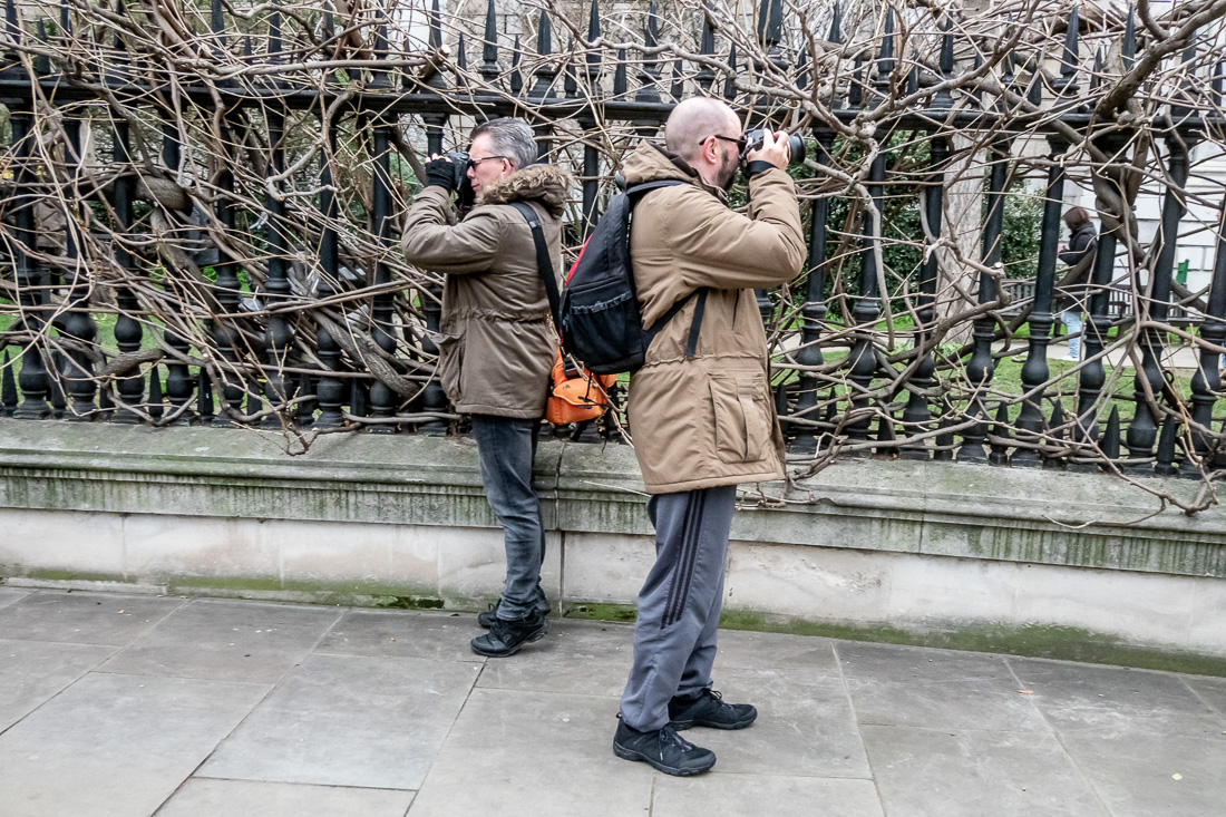 Candid street photography of two men with cameras in London.