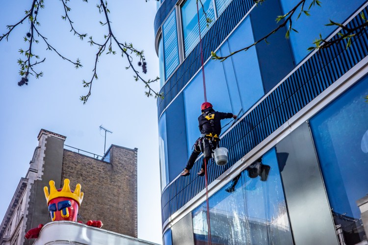 Candid street photography of a window cleaner on Oxford Street, London.