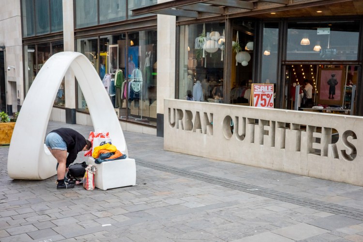 Candid street photography of a girl putting on a boot, outside Urban Outfitters in Bristol.