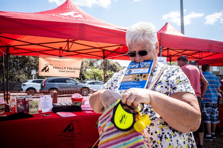 Candid street photography of a woman with a Dog Days program in her mouth, in Weston-super-Mare.