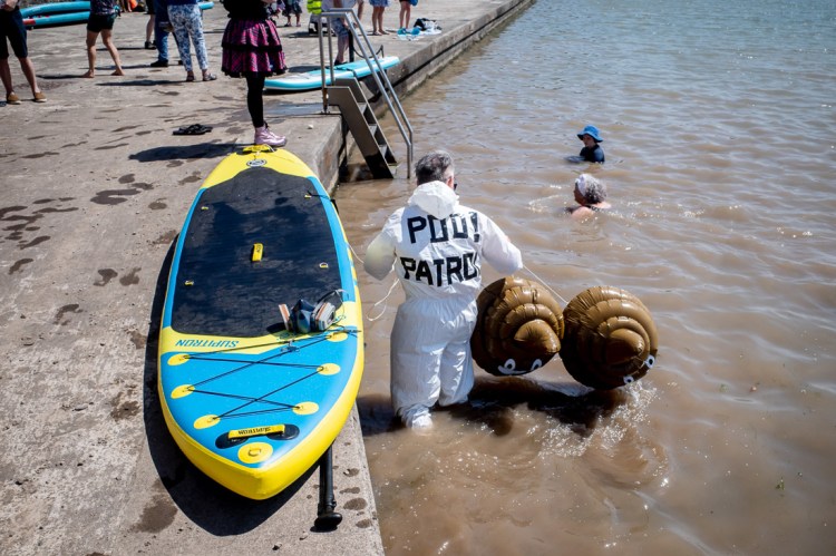 Candid street photography of a man from Poo Patrol holding inflatable poos in Marine Lake in Weston-super-Mare.