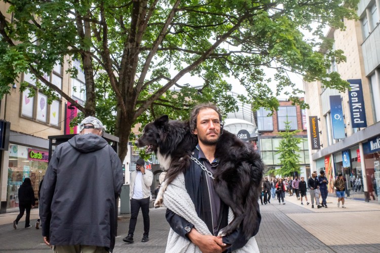 Candid street photography of a man carrying a dog around his neck in Bristol.
