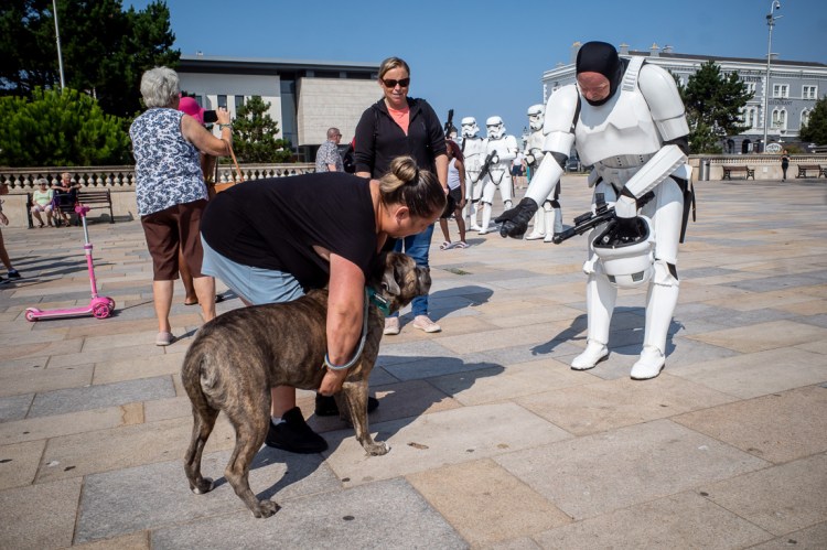 Street photography in Weston-super-Mare showing a person dressed as a Star Wars stormtrooper interacting with a dog on the promenade, with people watching and more costumed stormtroopers in the background.