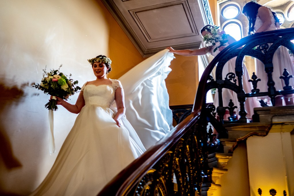 The bride is helped downstairs ahead of the wedding ceremony at Grittleton House in Wiltshire.