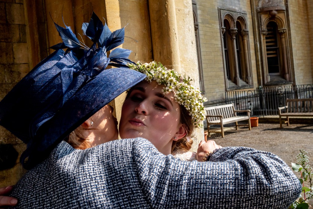 The bride kisses a guest, in a large wedding hat, at Grittleton House in Wiltshire.