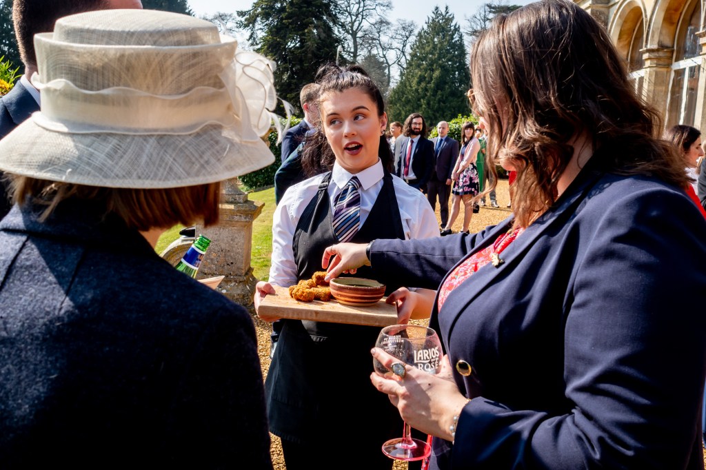 A waitress offers canapés to wedding guests at Grittleton House in Wiltshire.