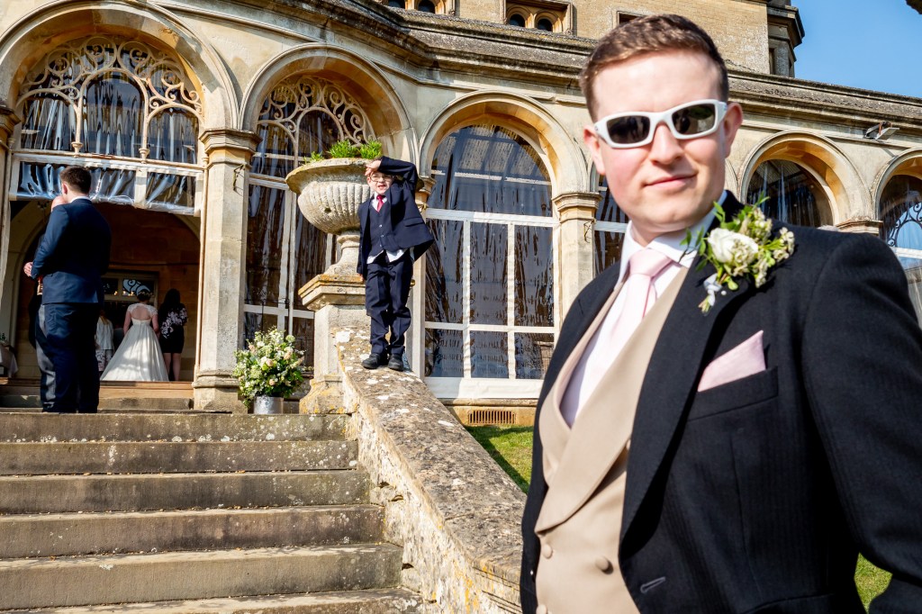 A wedding guest, in sunglasses, stares at the camera during a wedding at Grittleton House in Wiltshire.