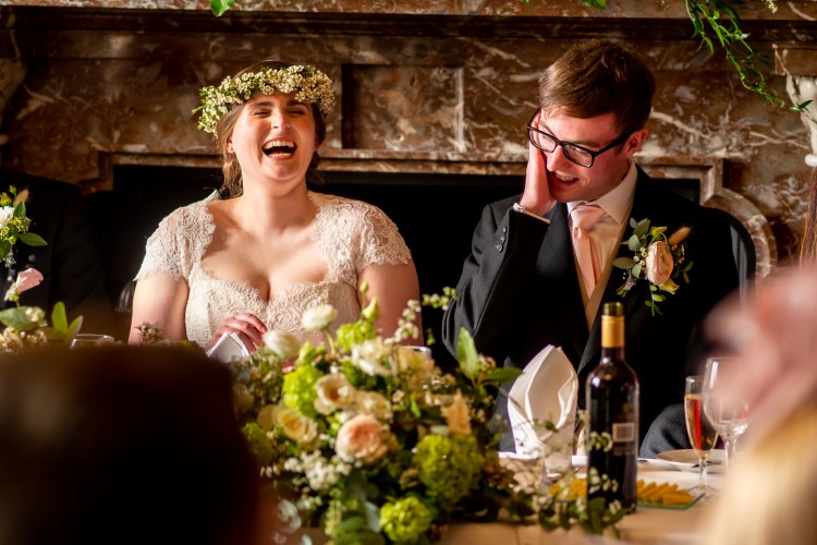 The bride laughs during the wedding speeches at Grittleton House in Wiltshire.