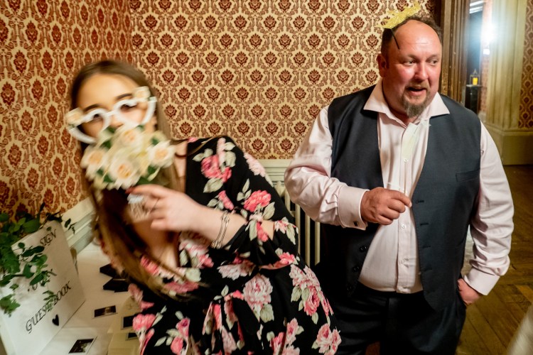 Guests playing with photobooth props during a wedding at Grittleton House in Wiltshire.
